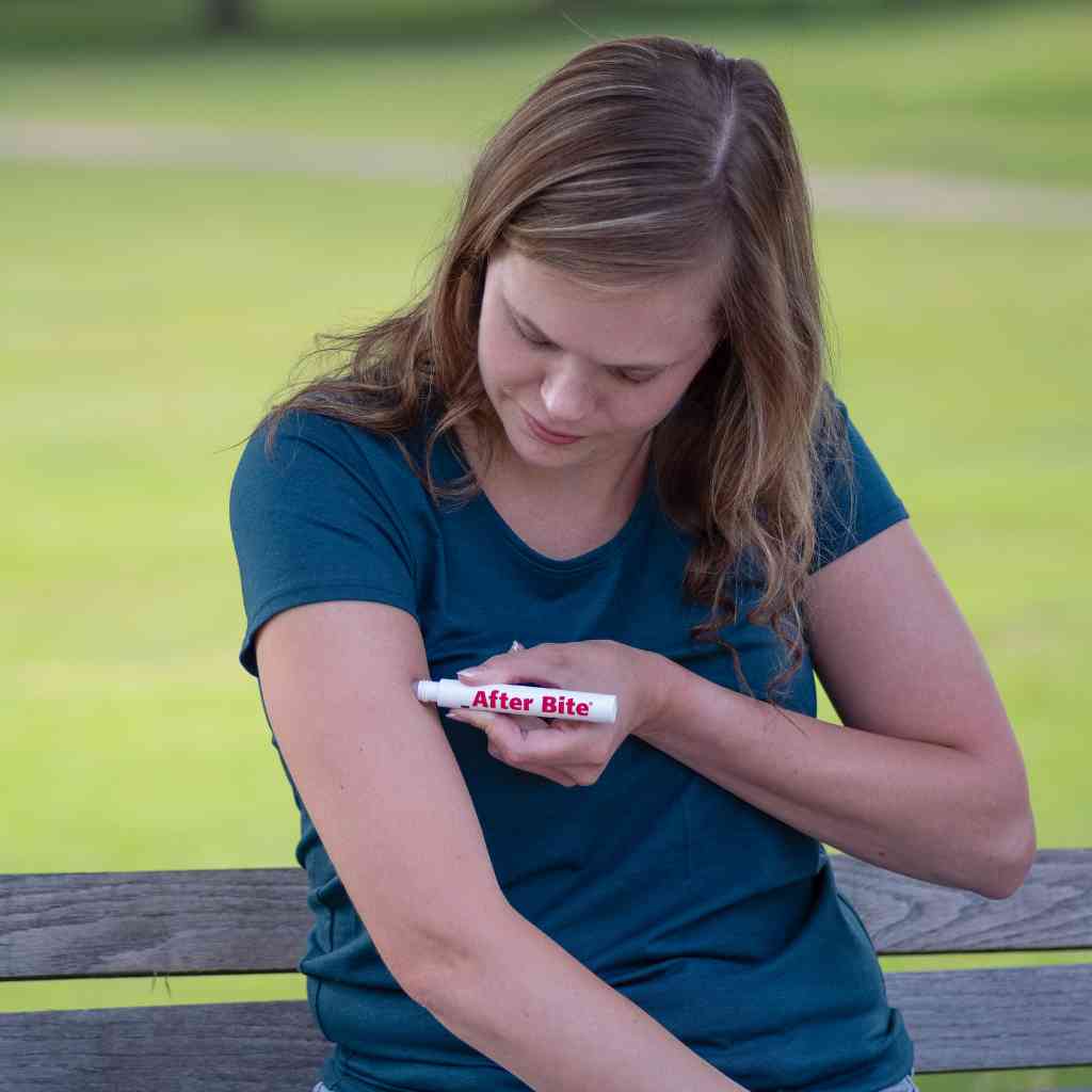 After Bite Advanced woman applying to arm while sitting on park bench
