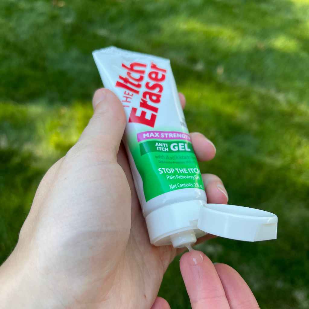 The Itch Eraser Gel squeezing tube contents onto finger in front of grass