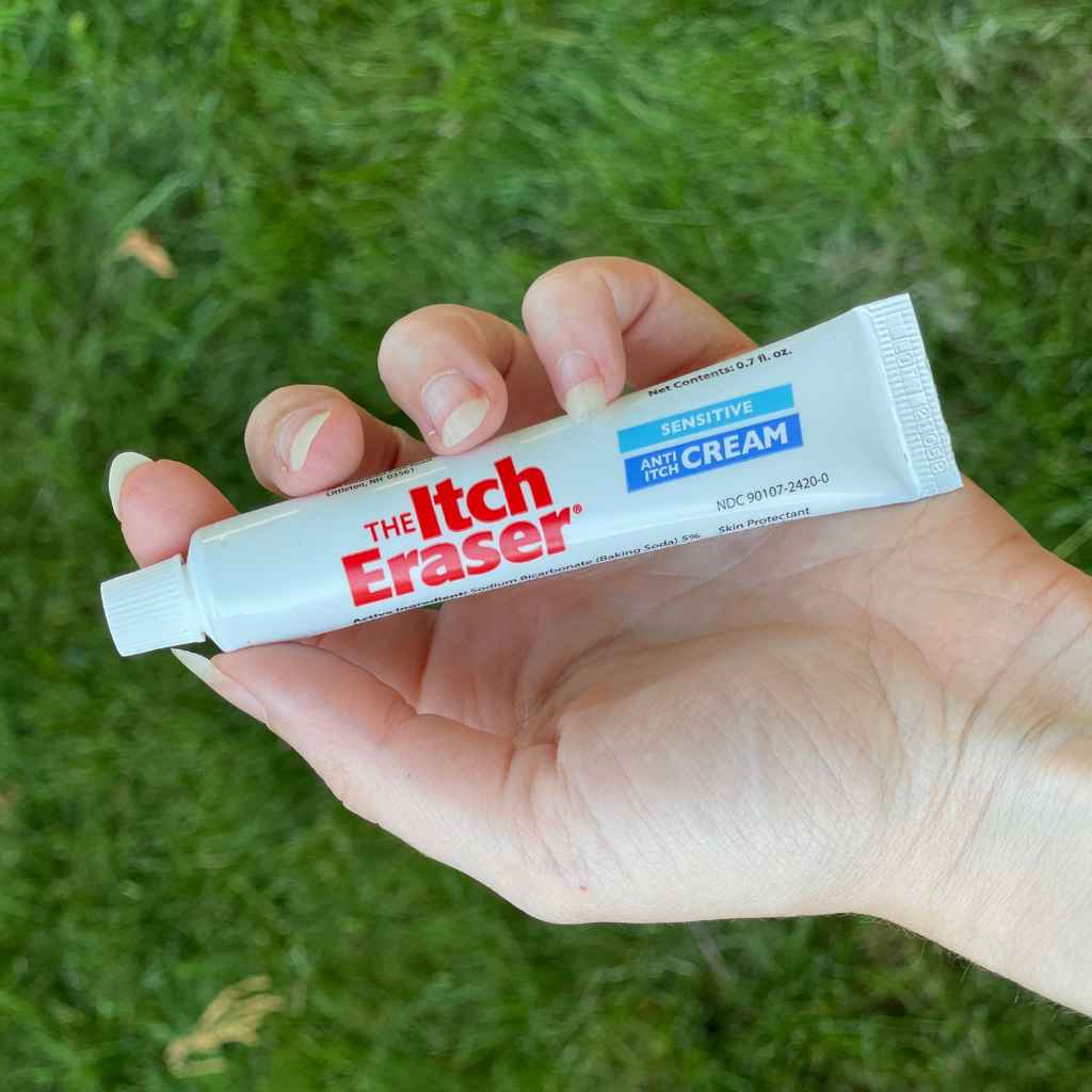 The Itch Eraser Sensitive Cream holding in hand in front of grass