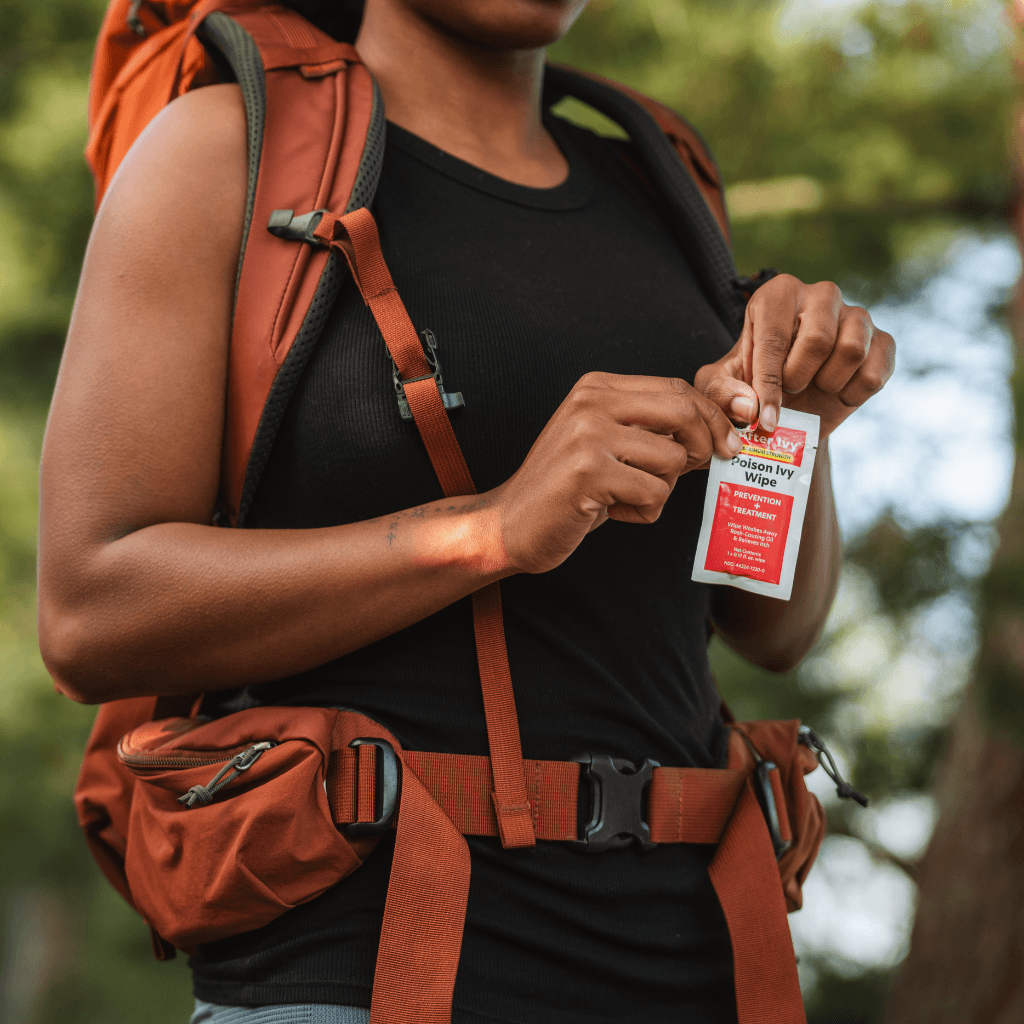 Woman wearing an orange backpack opening an After Ivy packet