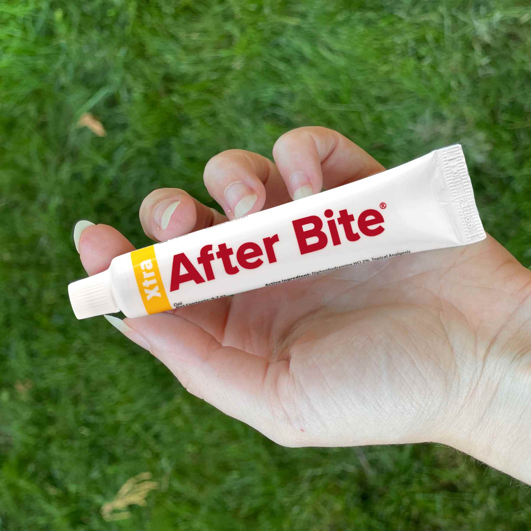 Person holding After Bite Xtra in hand over grass