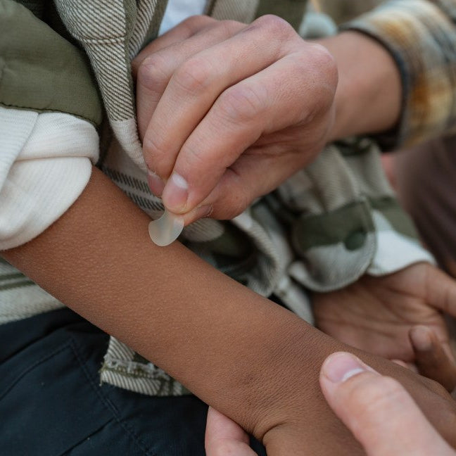 adult placing bug bite bandage on child's arm